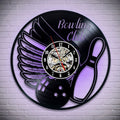 Black vinyl record clock with bowling ball and wings design, illuminated with a purple light effect, showcasing detailed gears.