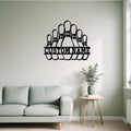 Black metal bowling pins wall art with “Custom Name” cutout displayed above a green sofa and side table with a potted plant