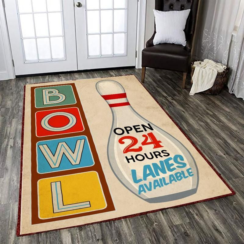 Living room setup featuring a retro bowling lanes area rug with colorful BOWL block letters and an ‘Open 24 Hours’ pin graphic
