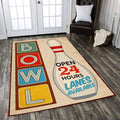 Living room setup featuring a retro bowling lanes area rug with colorful BOWL block letters and an ‘Open 24 Hours’ pin graphic