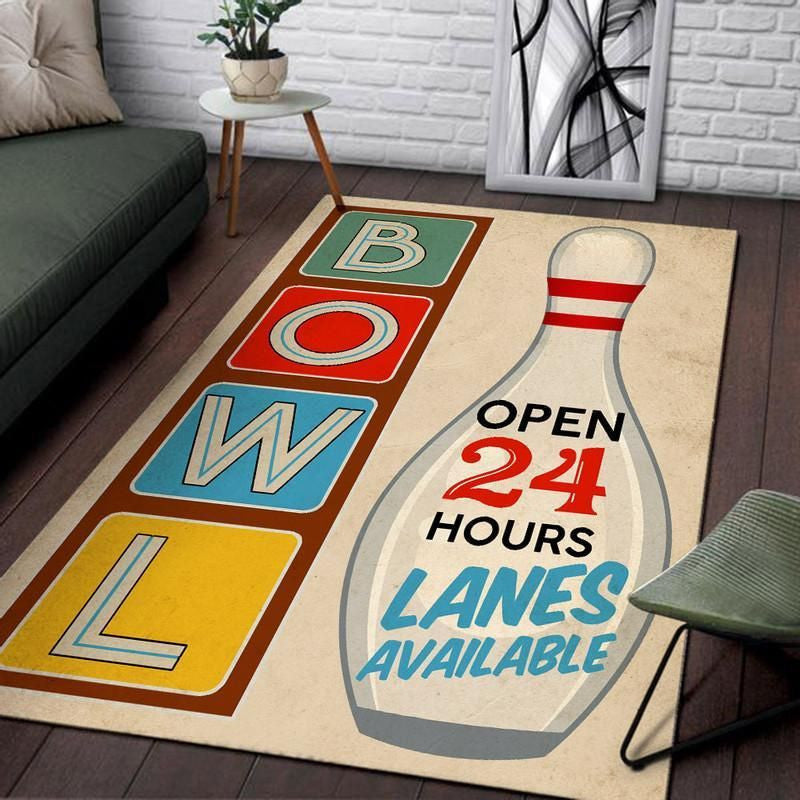 Living room setup featuring a retro bowling lanes area rug with colorful BOWL block letters and an ‘Open 24 Hours’ pin graphic