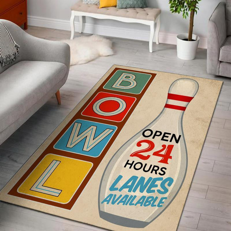 Rustic wood-floored entryway with a retro bowling lanes area rug displaying bold ‘Open 24 Hours’ message and BOWL letter art
