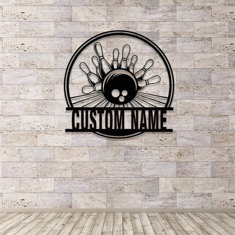 Powder-coated black metal bowling sign mounted on a smooth white wall, featuring a bowling ball and pins in a round frame with custom name bar.