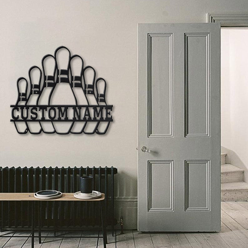 Bowling pins wall art with custom name displayed next to a tall gray door in a minimalist home.