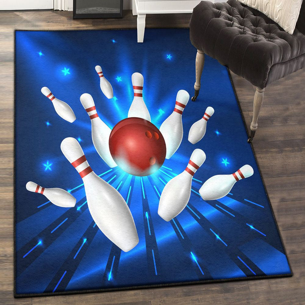 Area rug on hardwood floor featuring a red bowling ball striking white pins with blue radiant streaks and star accents